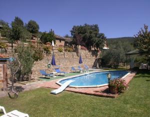 una piscina en un patio con sillas y sombrillas en Lauro, en Cortona