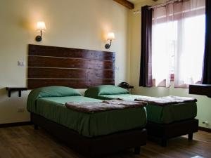 a bedroom with two beds with green sheets and a headboard at Sleep'n go Hotel in Fiumicino