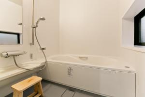 a white bathroom with a tub and a toilet at Hashiba-an in Kanazawa