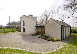 a small house with a tower on the side of it at Drum Gatelodge in Bushmills