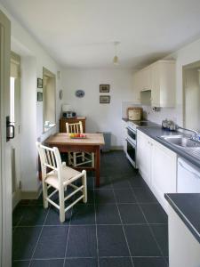 a kitchen with a sink and a table with a chair at Drum Gatelodge in Bushmills