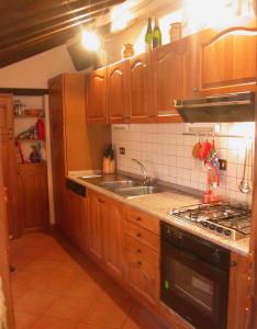 cocina con armarios de madera, fregadero y fogones en Lauro, en Cortona