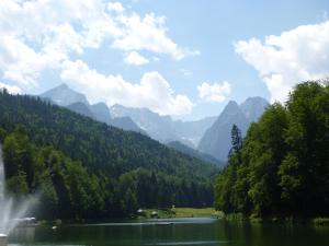 um lago com uma cascata e montanhas ao fundo em Gästehaus Andreas Hofer em Garmisch-Partenkirchen