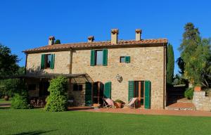 a large stone house with green shutters and a yard at Scansano Country House in Magliano in Toscana