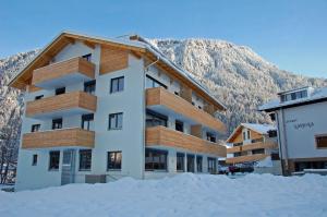 un immeuble avec de la neige devant une montagne dans l'établissement Appart Laijola, à Gaschurn