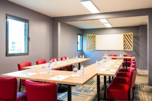 a conference room with long tables and red chairs at ibis Styles Rouen Val De Reuil in Val de Reuil