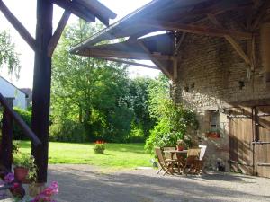 a stone building with a table and chairs in a yard at Chambre d'hotes Ferme de la Forlonge in Sauvigny-le-Beuréal