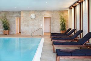 a lobby with a pool and lounge chairs and a clock at nordica Hotel Friesenhof in Büsum