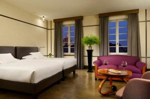 a hotel room with two beds and a table and a couch at Hotel Balestri - WTB Hotels in Florence