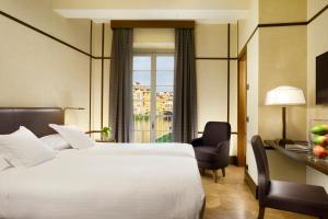 a hotel room with a bed and a desk and a window at Hotel Balestri - WTB Hotels in Florence