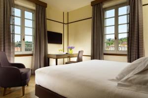 a hotel room with a bed and a desk and windows at Hotel Balestri - WTB Hotels in Florence