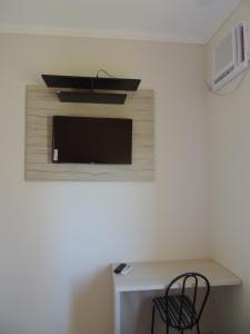 a room with a desk with a tv and a chair at Hotel Viracopos de Indaiatuba in Indaiatuba