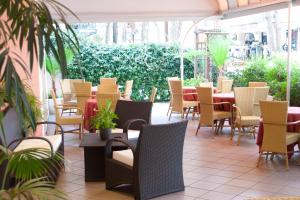 a patio with tables and chairs and plants at Hotel Myosotis in Riccione