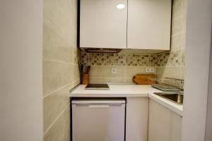 uma pequena cozinha com armários brancos e um lavatório em Cozy in the Heart of Alfama em Lisboa