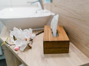 a bathroom counter with a sink and a wooden holder with flowers at Schlemmerhütte - Hotel in Langweid