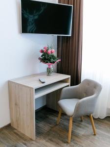 a desk with a vase of flowers and a chair at Schlemmerhütte - Hotel in Langweid
