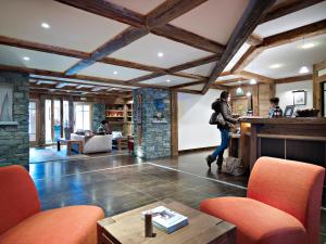 a woman walking through a lobby with a bar at CGH Résidences & Spas Le Ruitor in Sainte-Foy-Tarentaise