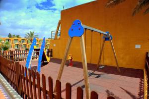 einen Spielplatz mit zwei Schaukeln und einer Rutsche in der Unterkunft Aparthotel la Piramide in Costa de Antigua