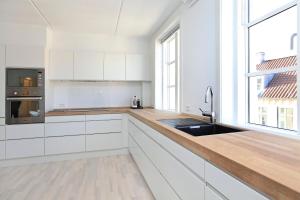 CPH Lux apartm, 2 FULL BATHROOMS 2th في كوبنهاغن: مطبخ بدولاب بيضاء وقمة كونتر خشبي