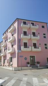 un edificio rosa al lado de una calle en Scano Comfort Inn, en Santa Teresa Gallura