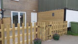 a wooden fence in front of a building with plants at Lord Byron Lodge in Blidworth