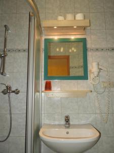 een badkamer met een wastafel, een spiegel en een douche bij Gasthof Schlosswirt in Klagenfurt