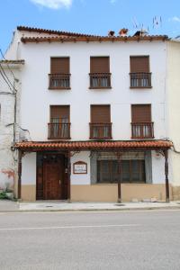 a white building with windows and a door at Hostal La Toba in Cañete