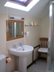 baño con lavabo, espejo y silla en The Black Bull Inn and Hotel, en Coniston