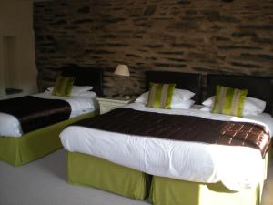Habitación de hotel con 2 camas y pared de piedra. en The Black Bull Inn and Hotel, en Coniston