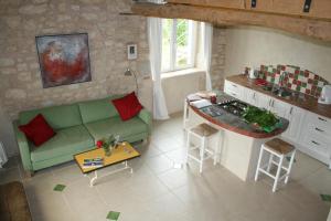 a living room with a green couch and a kitchen at Puechblanc Gîtes et Chambre d'hôte dans le Triangle d'or Gaillac-Albi-Cordes sur Ciel in Fayssac