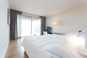 a white bedroom with a large white bed and a window at Palmares Beach House Hotel - Adults Only in Lagos