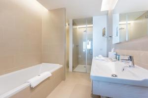 a bathroom with a sink, mirror, and bathtub at Palmares Beach House Hotel - Adults Only in Lagos