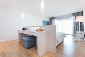 a white bedroom with a bed and a desk at Palmares Beach House Hotel - Adults Only in Lagos