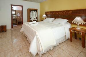 1 dormitorio con 1 cama blanca grande y 2 lámparas en Pousada Neuza Barbosa, en Tiradentes