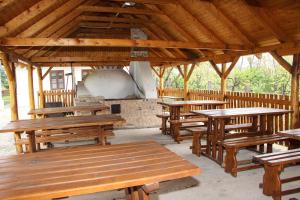 a group of wooden picnic tables in a pavilion at A cigándi bíró háza in Cigánd