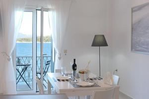 コルフ・タウンにあるElia Sea View Apartmentの白いダイニングルーム(ワイン1本とテーブル付)