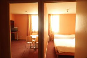 a hotel room with a bed and a desk and a table at Geneva Residence in Gaillard