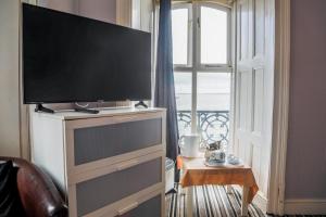 uma televisão de ecrã plano numa cómoda com uma janela em Anglesey Arms em Caernarfon