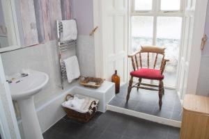ein Bad mit einem Stuhl, einem Waschbecken und einem Fenster in der Unterkunft Anglesey Arms in Caernarfon