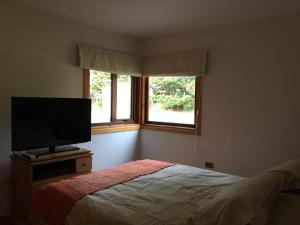 1 dormitorio con 1 cama y TV de pantalla plana en Cabañas Posadas De Coyhaique, en Coyhaique
