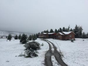 a house in a snow covered field with a dirt road at Cabañas Posadas De Coyhaique in Coihaique