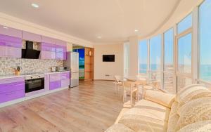 a kitchen and living room with purple cabinets and a table at Arcadia Apartment Gagarin plaza in Odesa