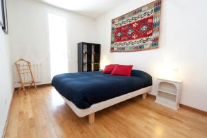 Schlafzimmer mit einem Bett mit blauer Bettwäsche und roten Kissen in der Unterkunft Penthouse Vallespir in Barcelona