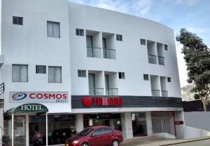 un bâtiment blanc avec une voiture rouge garée devant. dans l'établissement Hotel Cosmos Sincelejo, à Sincelejo