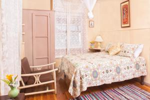 a bedroom with a bed and a chair and a window at Barbecue Heritage Gardens Cottage - JM in Newcastle