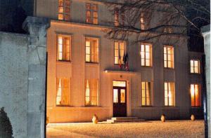 um grande edifício com as suas portas iluminadas à noite em La Villa Champagne Ployez-Jacquemart em Ludes