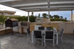 een patio met een tafel en stoelen en een grill bij Punta Di Mola in Marina di Ragusa