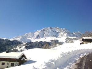 a snow covered mountain in front of a house at Le Foueustarle in La Giettaz