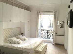 een witte slaapkamer met een bed en een raam bij Luxe Apartment 165m2 8pers Victor Hugo trocadero foch Champs Elysées in Parijs