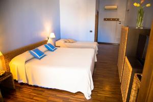 1 dormitorio con 1 cama blanca con almohadas azules y TV en Hotel Cetarium, en Castellammare del Golfo